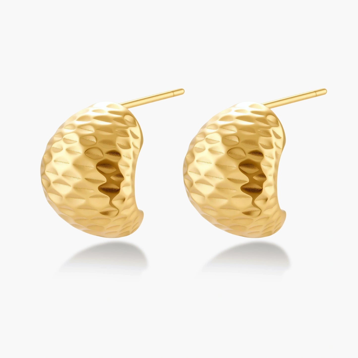 Pair of textured gold-plated sterling silver huggie earrings with dimpled surface finish on cream background.