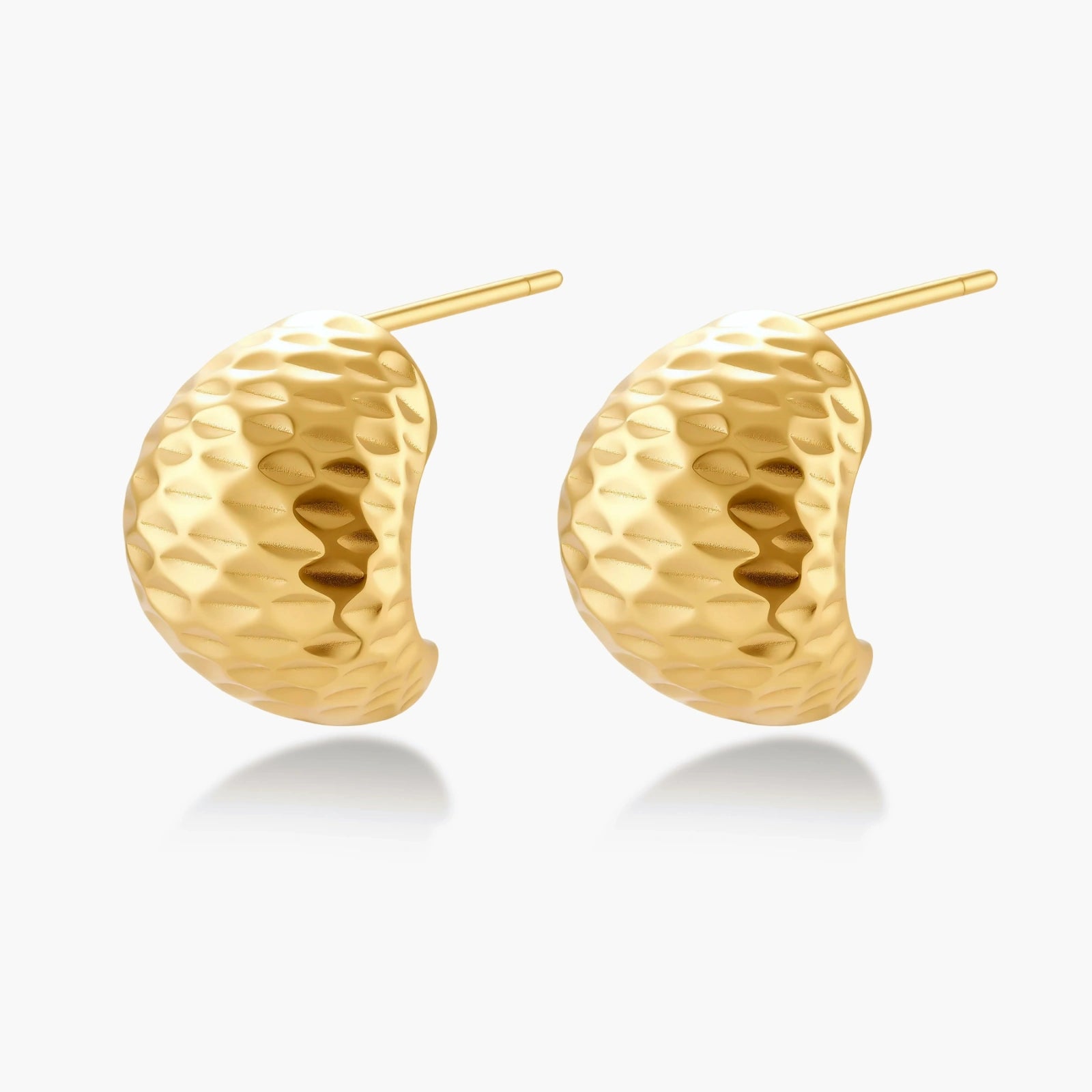 Pair of textured gold-plated sterling silver huggie earrings with dimpled surface finish on cream background.