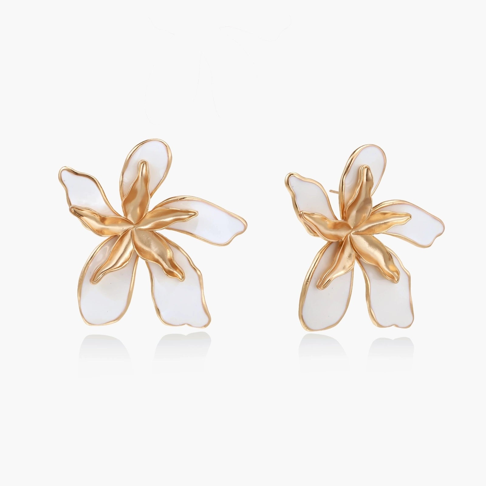 White enamel tropical flower earrings with sculptural gold-plated center and organic petal design on cream background