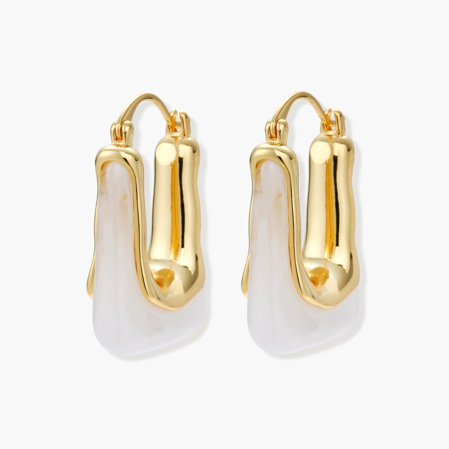 Sculptural gold-plated hoop earrings with flowing curved design and lever-back closure on cream background.