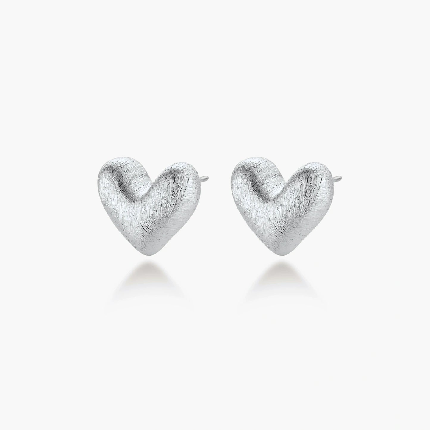 Pair of brushed platinum-plated 925 sterling silver puffy heart stud earrings on a cream background.