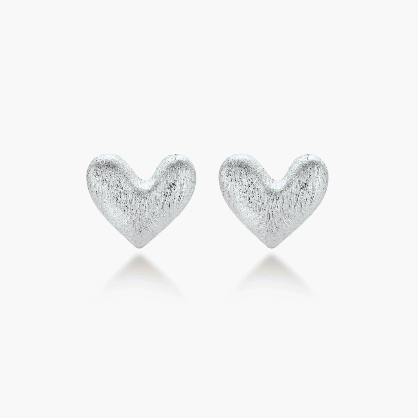 Pair of brushed platinum-plated 925 sterling silver puffy heart stud earrings on a cream background.