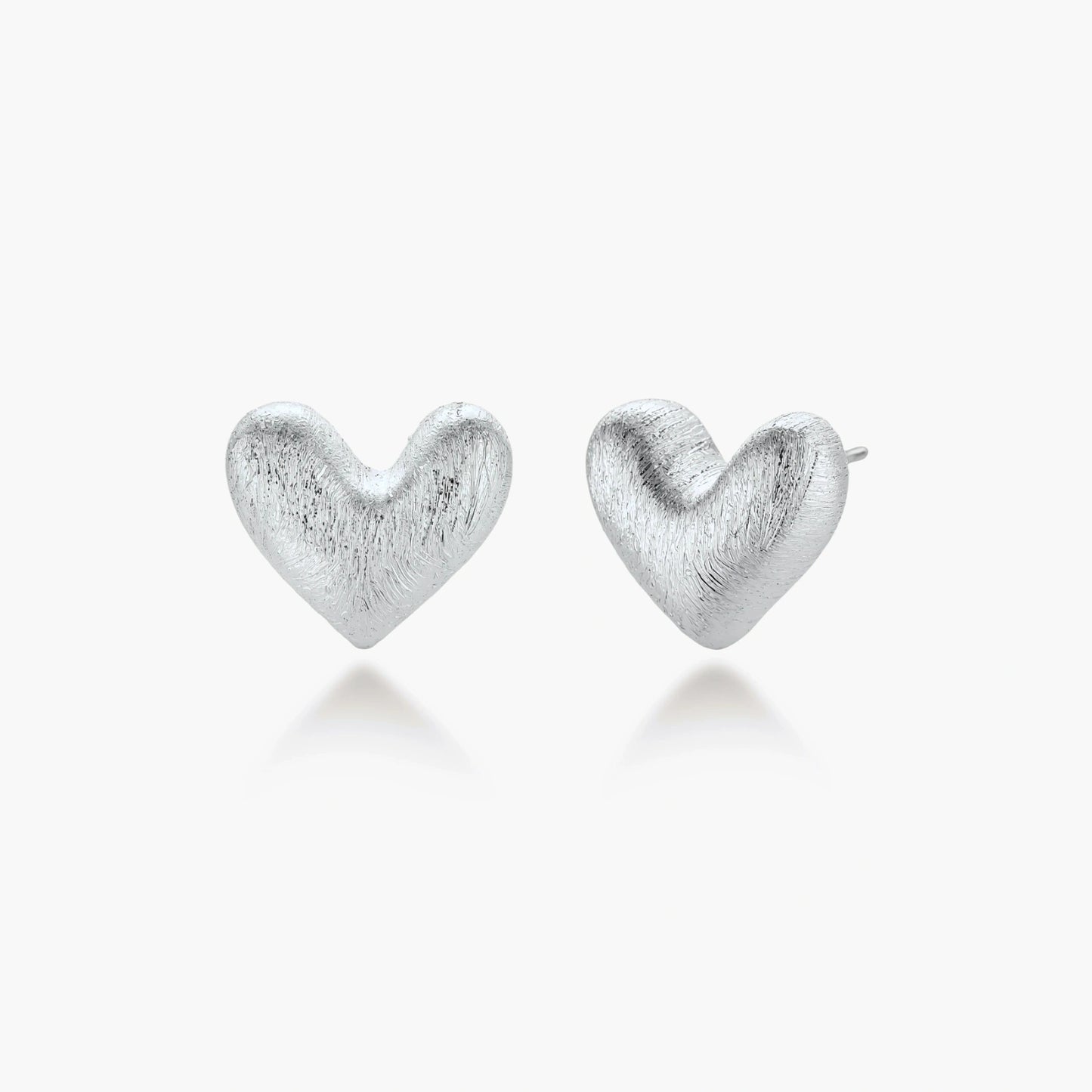 Pair of brushed platinum-plated 925 sterling silver puffy heart stud earrings on a cream background.