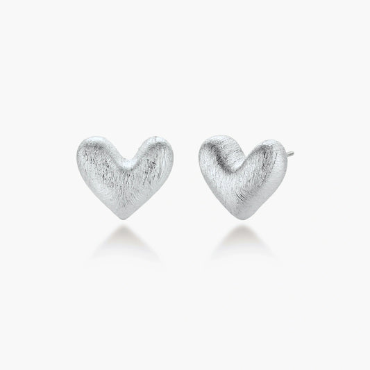 Pair of brushed platinum-plated 925 sterling silver puffy heart stud earrings on a cream background.