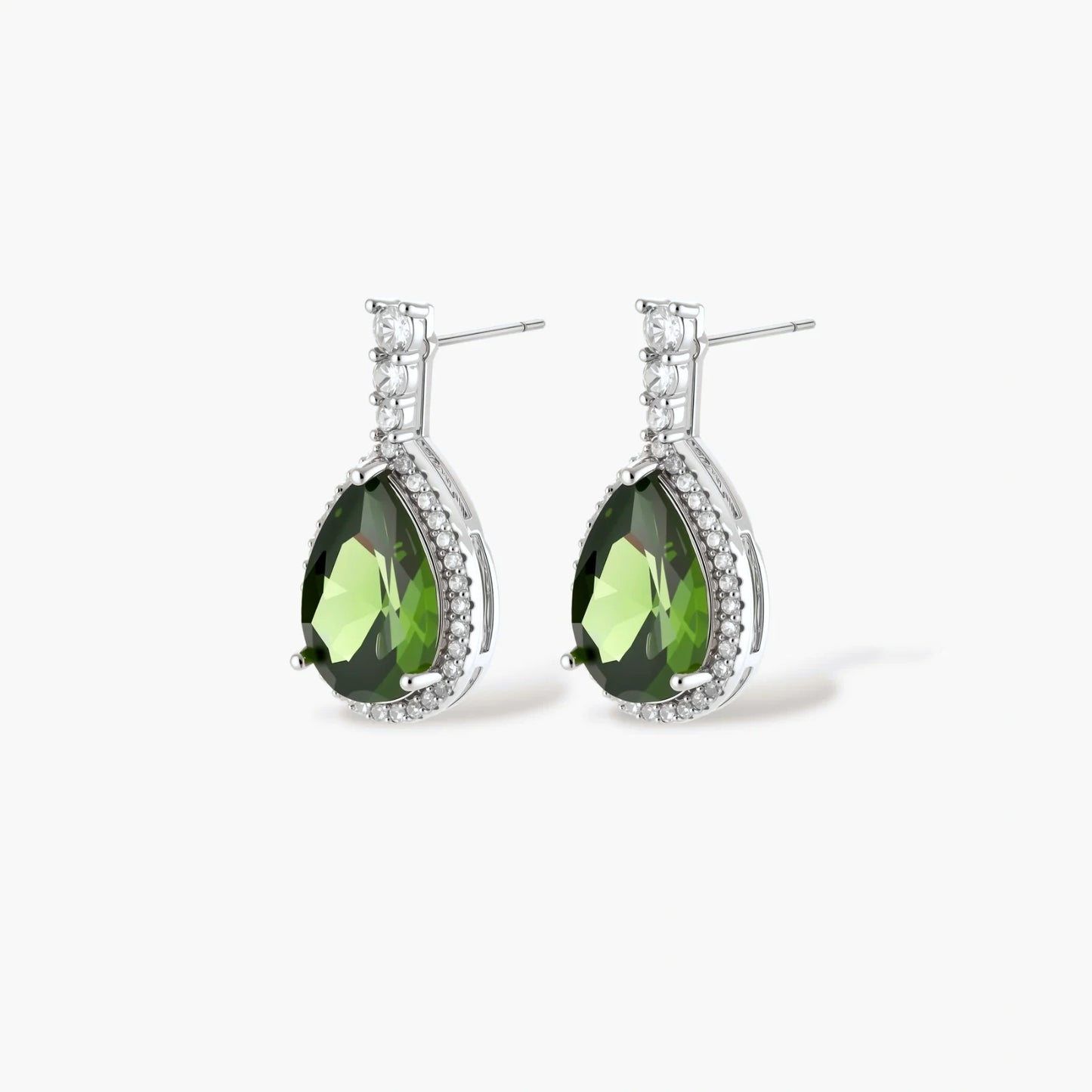 White gold plated jewelry set with green teardrop gemstones and cubic zirconia halos on cream background.